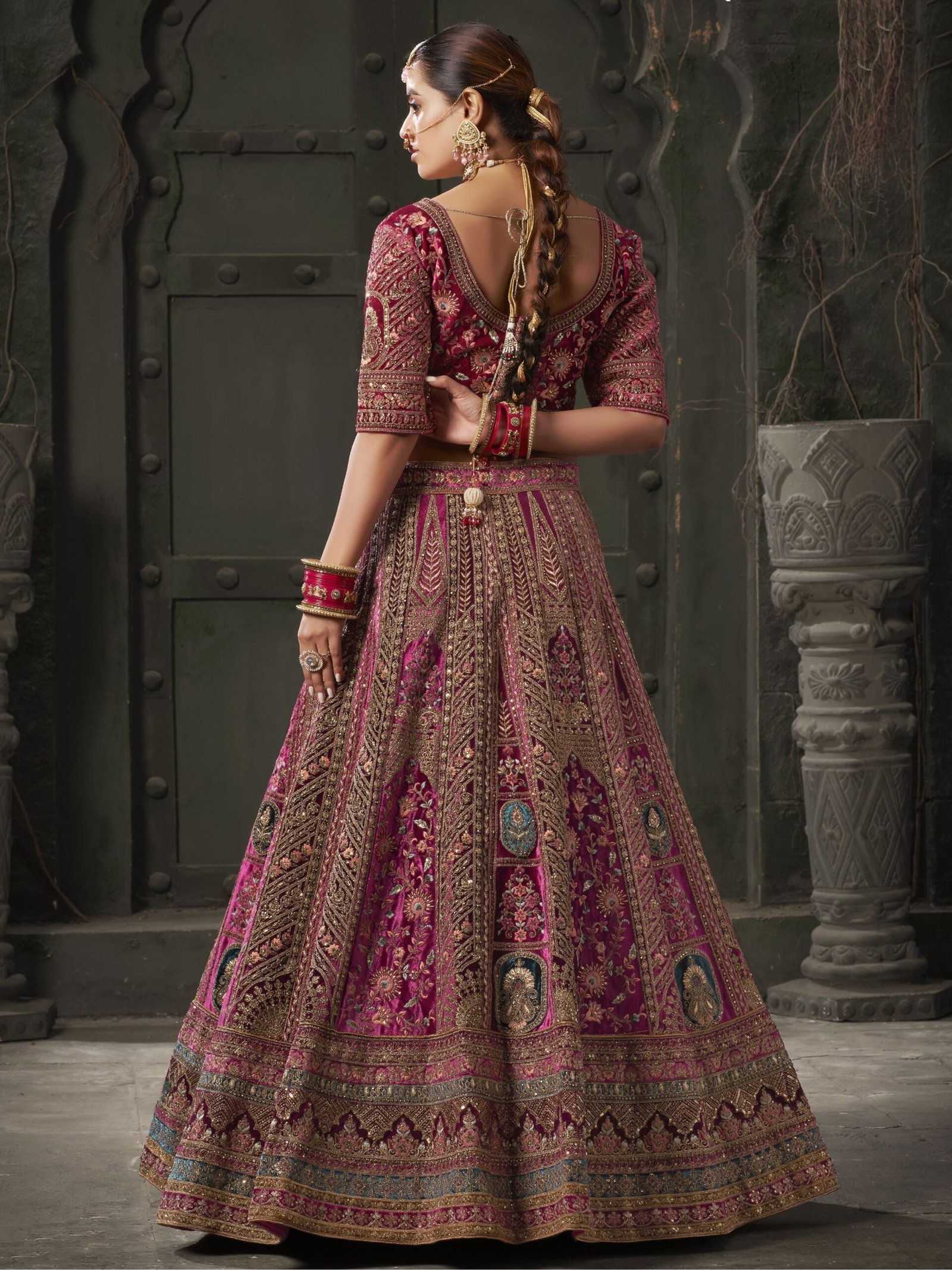 Indulge in the regal allure of this magnificent maroon color velvet bridal lehenga, meticulously crafted to adorn the bride in timeless elegance and sophistication. Luxuriously crafted from sumptuous velvet material, this ensemble is adorned with a mesmerizing array of embellishments, including multi-thread work, sequin work, diamond work, zari work, velvet embroidered patchwork, and fancy dori work, ensuring a breathtakingly opulent aesthetic. Accompanying the lehenga is a matching velvet choli, intricately detailed with similar multi-thread work, sequin work, diamond work, zari work, embroidered work, and fancy dori work, creating a harmonious and refined ensemble. The semi-stitched design of the lehenga offers a comfortable fit of up to 42 inches, allowing for ease of movement and flexibility. Additionally, the un-stitched choli material provides the opportunity for customization, ensuring a tailored and flattering silhouette for the bride. Completing the ensemble are two double dupattas crafted from similar maroon net and velvet material, adorned with exquisite lace work and butta work on all four sides. These dupattas add an ethereal touch of romance and grace, draping gracefully over the shoulders and enhancing the overall beauty of the bridal look. Whether worn traditionally or styled in a modern manner, these dupattas add a layer of sophistication and glamour to the ensemble. Draping yourself in this featured maroon color velvet bridal lehenga is not merely about wearing a garment; it's about embodying a sense of timeless beauty and refinement. Each element of this ensemble has been thoughtfully curated to ensure that the bride radiates confidence and grace on her special day. Prepare to receive an abundance of compliments as you showcase your impeccable taste and sophisticated style with this breathtaking bridal lehenga, destined to make you the epitome of elegance and grace on your wedding day. Disclaimer: Slight color variation may occur due to photographic reasons. - Image 3