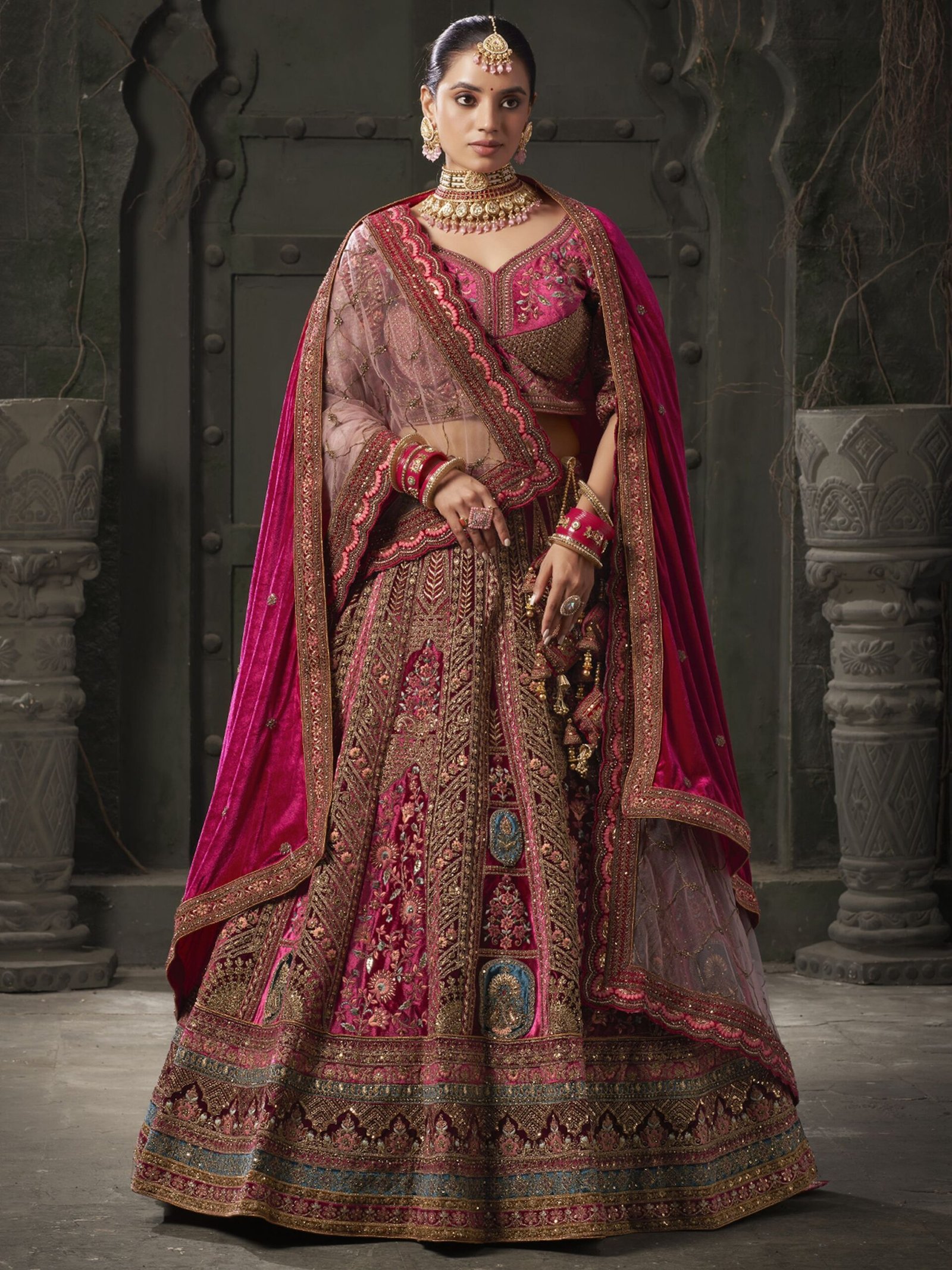 Indulge in the regal allure of this magnificent maroon color velvet bridal lehenga, meticulously crafted to adorn the bride in timeless elegance and sophistication. Luxuriously crafted from sumptuous velvet material, this ensemble is adorned with a mesmerizing array of embellishments, including multi-thread work, sequin work, diamond work, zari work, velvet embroidered patchwork, and fancy dori work, ensuring a breathtakingly opulent aesthetic. Accompanying the lehenga is a matching velvet choli, intricately detailed with similar multi-thread work, sequin work, diamond work, zari work, embroidered work, and fancy dori work, creating a harmonious and refined ensemble. The semi-stitched design of the lehenga offers a comfortable fit of up to 42 inches, allowing for ease of movement and flexibility. Additionally, the un-stitched choli material provides the opportunity for customization, ensuring a tailored and flattering silhouette for the bride. Completing the ensemble are two double dupattas crafted from similar maroon net and velvet material, adorned with exquisite lace work and butta work on all four sides. These dupattas add an ethereal touch of romance and grace, draping gracefully over the shoulders and enhancing the overall beauty of the bridal look. Whether worn traditionally or styled in a modern manner, these dupattas add a layer of sophistication and glamour to the ensemble. Draping yourself in this featured maroon color velvet bridal lehenga is not merely about wearing a garment; it's about embodying a sense of timeless beauty and refinement. Each element of this ensemble has been thoughtfully curated to ensure that the bride radiates confidence and grace on her special day. Prepare to receive an abundance of compliments as you showcase your impeccable taste and sophisticated style with this breathtaking bridal lehenga, destined to make you the epitome of elegance and grace on your wedding day. Disclaimer: Slight color variation may occur due to photographic reasons.