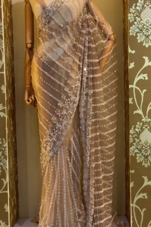 Luxurious Designer Net Saree in Nude Beige Shade with All-Over Hand Embellished Sequins, Pearls, and Beadwork in Wavy Pattern, Paired with Matching Blouse – Ideal for Glamorous Evening Parties, Receptions, and Modern Bridal Looks