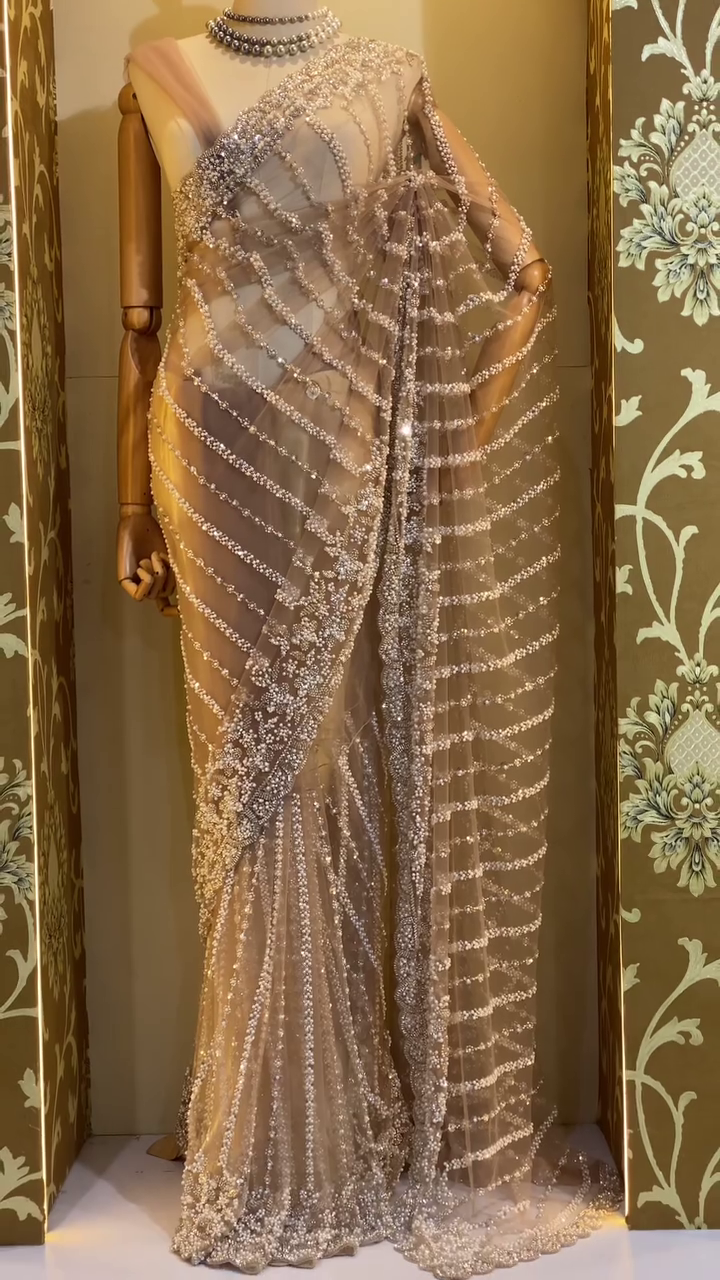 Luxurious Designer Net Saree in Nude Beige Shade with All-Over Hand Embellished Sequins, Pearls, and Beadwork in Wavy Pattern, Paired with Matching Blouse – Ideal for Glamorous Evening Parties, Receptions, and Modern Bridal Looks